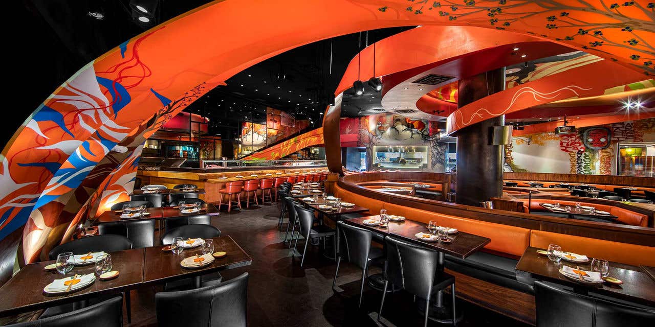 A vibrant restaurant with dark floors and chairs and bright orange decor throughout. 